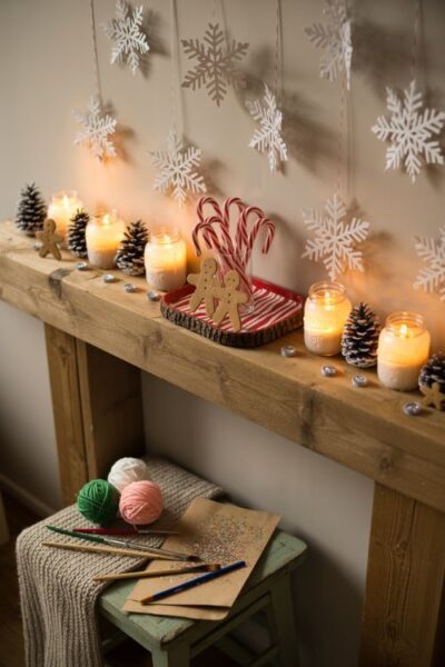 Festive DIY Christmas scene with snowy mason jars, pinecone candle holders, peppermint tray centerpiece, and handmade paper snowflakes, showcasing budget-friendly holiday decorations.