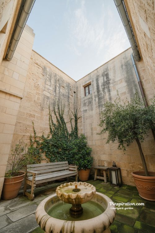 Courtyard garden with stone fountain olive trees and quiet enclosed Mediterranean home atmosphere