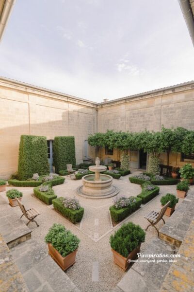 French courtyard garden ideas with balanced layout symmetry and organic flow design with central fountain and stone courtyard structure