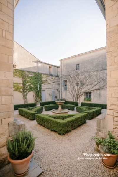 French courtyard garden ideas with stone fountain boxwood hedges and gravel structured garden design