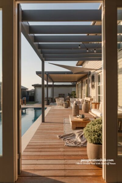 Pergola covered above ground pool deck attached to house with cozy lounge area