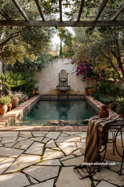 Spanish style natural pool with terracotta coping hand painted tiles and stone fountain in a garden