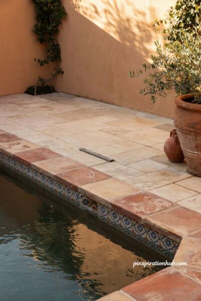 Spanish style pool with terra cotta tile coping and warm stone patio