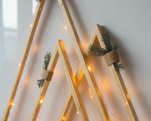 minimalist geometric wooden christmas tree wall decor with warm fairy lights and pinecone accents in modern living room