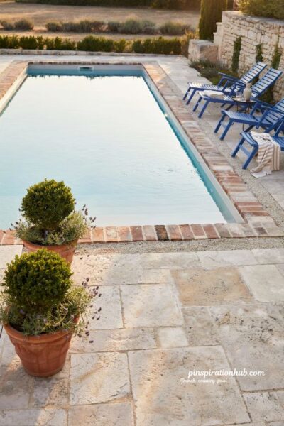 Blue loungers against stone and brick French country pool edging with elegant color contrast