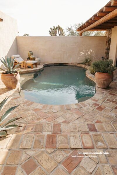 Custom shaped Mediterranean pool with adobe pavers and desert villa backyard style
