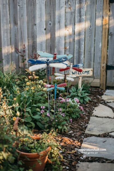 DIY license plate dragonfly garden art along a rustic pathway in a colorful backyard