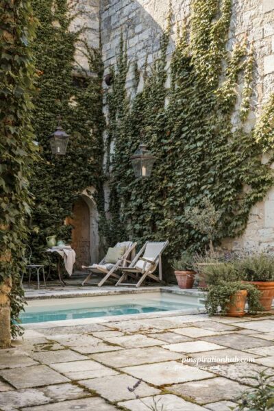 French country courtyard pool with ivy covered stone wall and timeless European charm