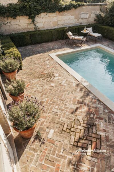 French country pool with herringbone brick patio and timeless geometric garden design