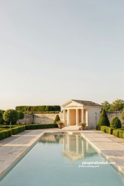 French country pool with neoclassical white column pavilion and formal hedge garden symmetry