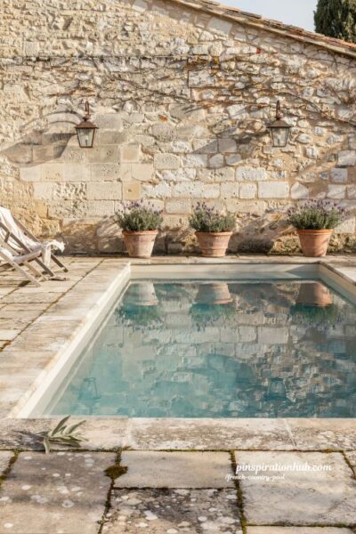 French country rectangular pool beside rustic stone cottage wall with timeless countryside charm