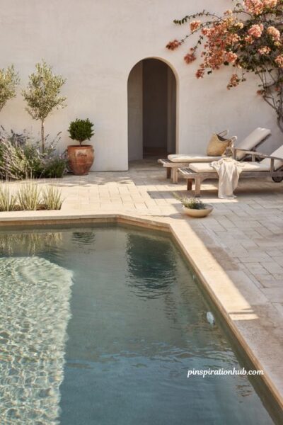 Low salt pool design with travertine patio sun loungers and natural stone coping