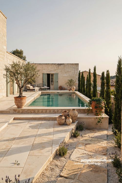 Mediterranean pool design with travertine decking and terracotta pots in a luxury European style backyard