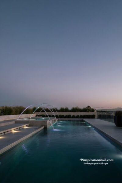 rectangle pool and spa with deck jets and illuminated laminars modern luxury backyard design with glowing water arcs at night