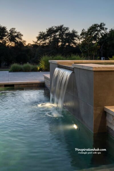 rectangle pool and spa with sheer descent waterfall modern luxury backyard design featuring illuminated glass like water flow