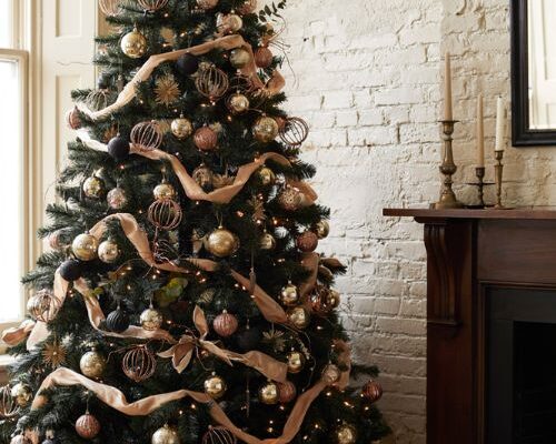 A sophisticated black Christmas tree with warm gold and copper ornaments in a cozy historic brownstone living room.
