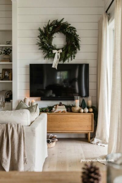 Christmas tv wall decor with oversized evergreen wreath above screen and cozy living room styling