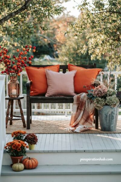 Cozy fall outdoor porch decor with copper accents pink and orange pillows and galvanized bucket