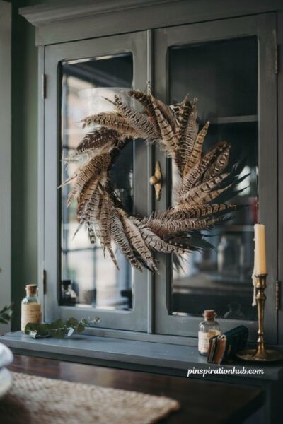 Diy faux pheasant feather wreath with spiral effect on a vintage glass cabinet for moody autumn home decor