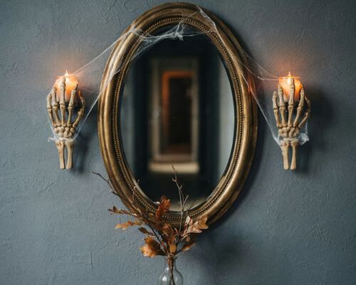 Dramatically lit skeleton hand wall sconces and mirror halloween entryway decor