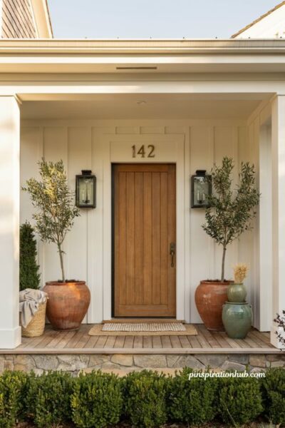 Farmhouse porch ideas with symmetrical planters framing the front door