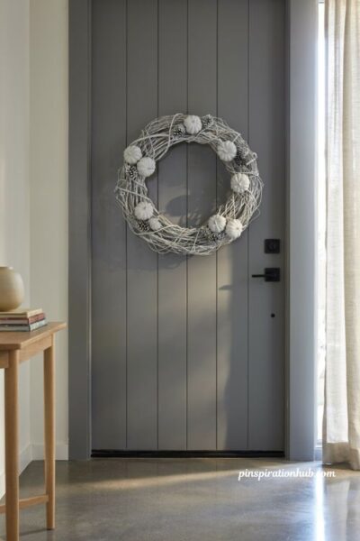 Monochromatic painted white grapevine wreath on modern grey front door for minimalist fall decor