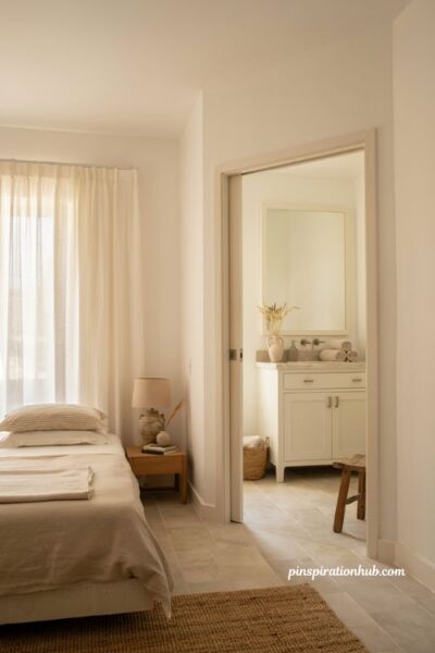 Neutral coastal bedroom with painted bathroom vanity and framed mirror for a cohesive ensuite design