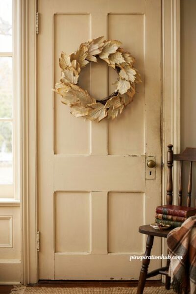 Vintage book page leaf wreath on a warm white front door for a literary autumn entryway decor