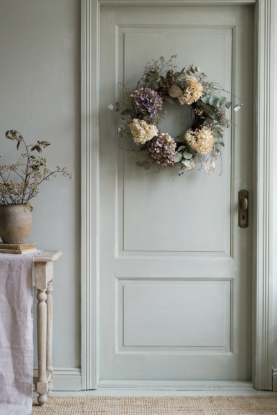 Dried hydrangea and twig wreath on a sage green front door for elegant transitional fall decor