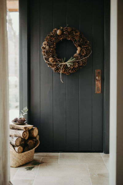 Foraged pinecone wreath on a charcoal black front door for minimalist rustic autumn entryway decor
