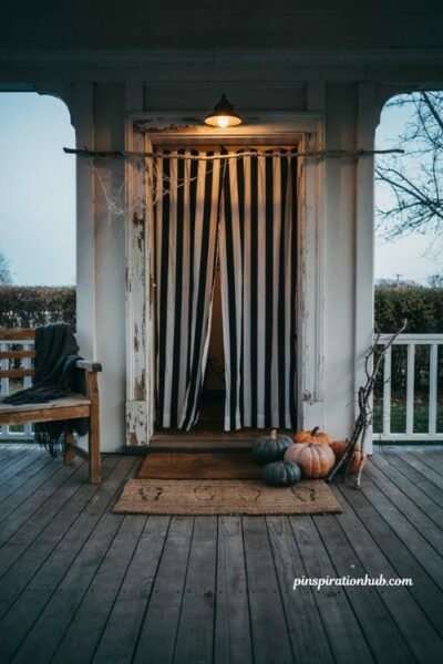 Black-and-white striped curtains frame a dramatic Halloween entryway, creating a theatrical, spooky entrance with minimal cost and effort.