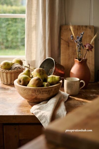 Cozy fall kitchen decor with green and golden pears in a wooden bowl copper and dried flowers