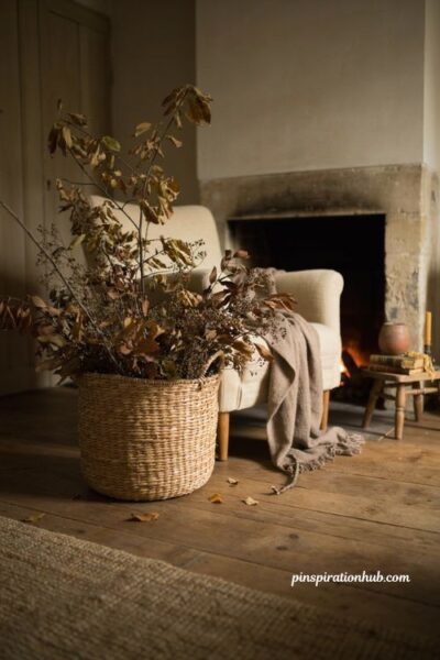 Cozy fall living room with woven basket filled with dried autumn branches leaves and seasonal stems