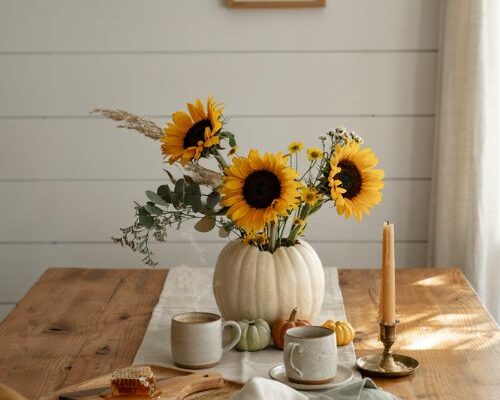 Sunflower and white pumpkin flower centerpiece idea for a cozy fall breakfast table