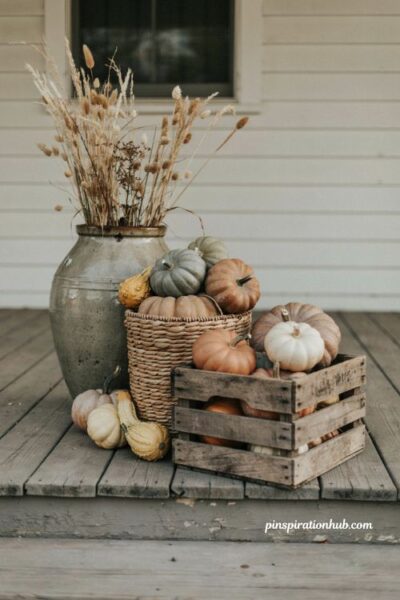 mixed pumpkin and gourd fall porch decor with smooth pumpkins bumpy gourds wooden crates woven baskets and stoneware crocks