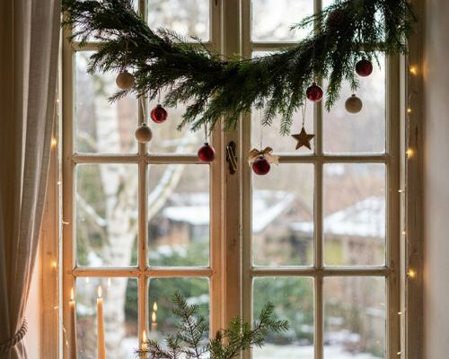 Christmas window decorations with evergreen garland and warm lights