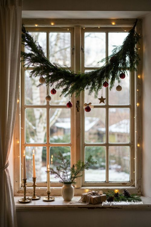 Christmas window decorations with evergreen garland and warm lights