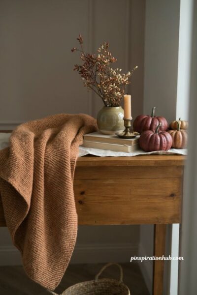 Fall entry table decor with draped camel knit throw and burgundy pumpkins