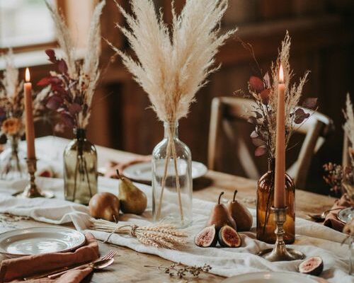 Fall wedding table decor ideas with pampas grass wheat vintage bottles candles and seasonal fruit