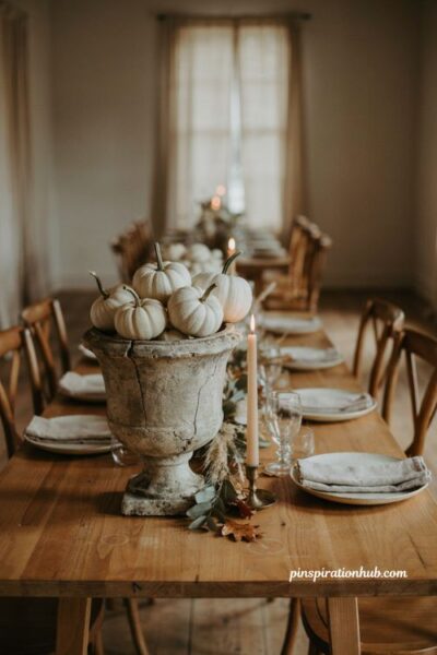 Fall wedding table decor with white pumpkins in a stone urn on a rustic wooden table
