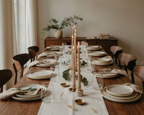 Modern Thanksgiving table with white linen candles and greenery