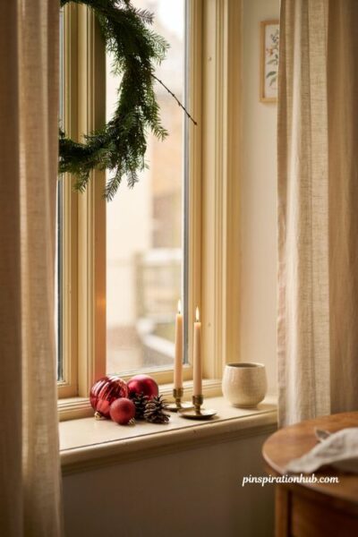 Simple red Christmas window decorations with greenery and candles